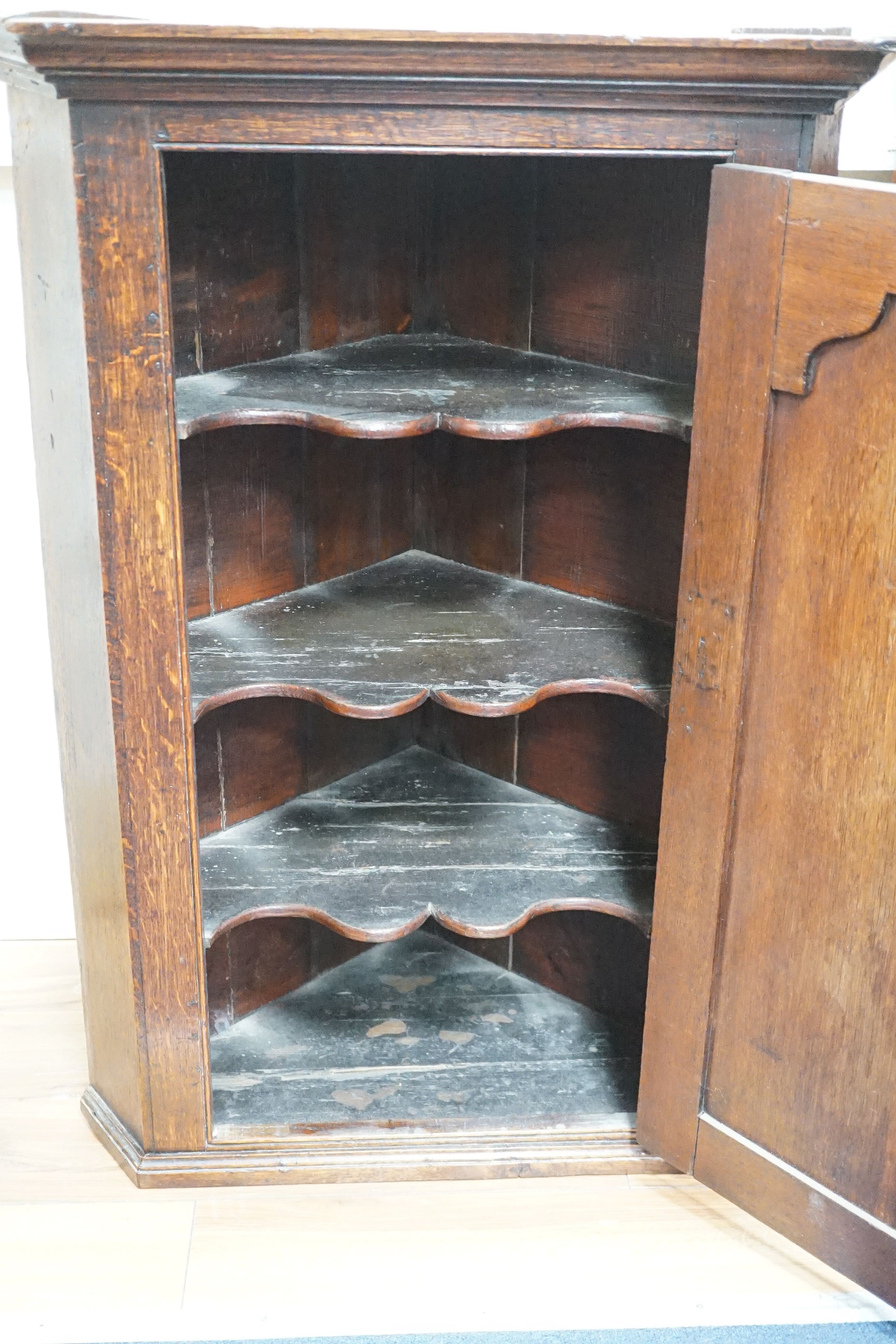 An 18th century panelled oak hanging corner cabinet, width 66cm, depth 43cm, height 93cm